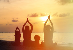 family silhouettes doing yoga at sunset sea